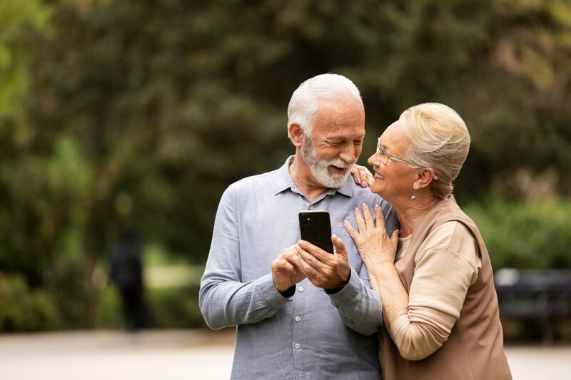 Pareja de abuelos mirando el celular y riendo.