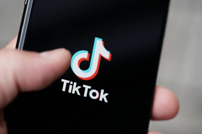 Una mano sosteniendo un celular en donde se ve la aplicación de Tik Tok.